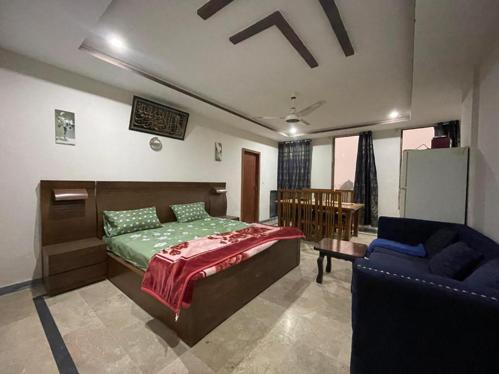 a bedroom with a bed and a blue chair at Own It Hotel in Islamabad
