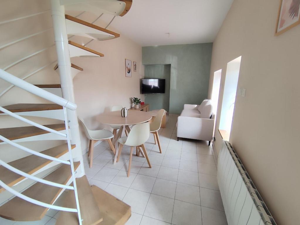 a staircase in a living room with a table and chairs at La petite Amandaise in Saint-Amand-sur-Sèvre