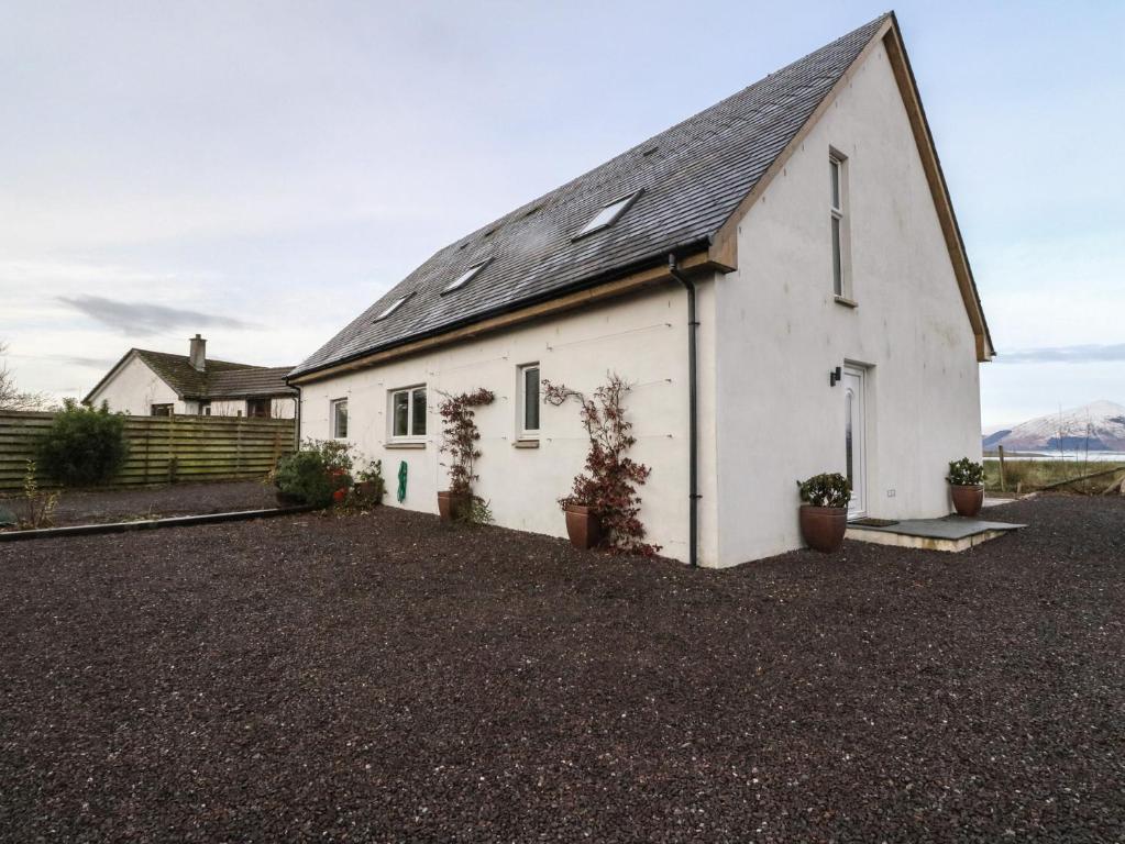 a white church with a black roof on a gravel driveway at Lurach House in Appin