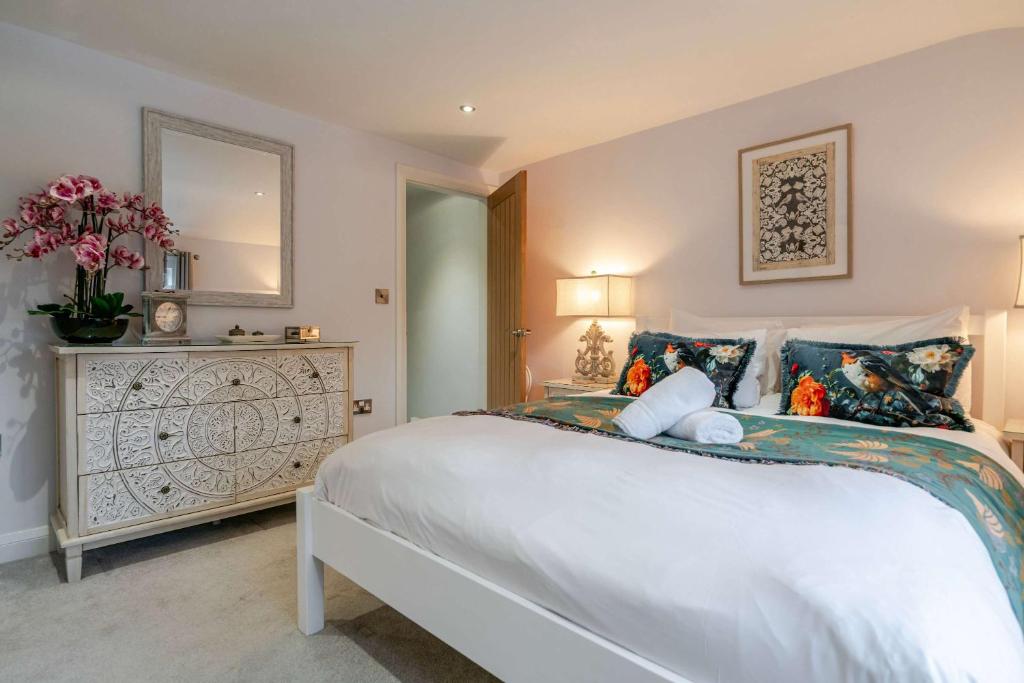 a bedroom with a large white bed and a dresser at The Knutsford Cottage in Knutsford