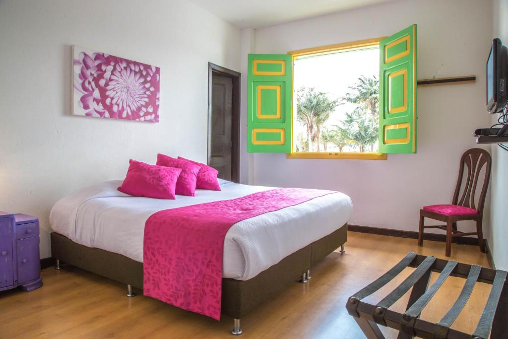 a bedroom with a bed with pink pillows and a window at La Posada de la Plaza in Salento