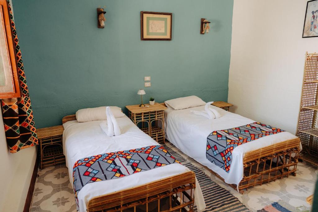 a room with two beds and two tables in it at Harmonia House in Al Karnak