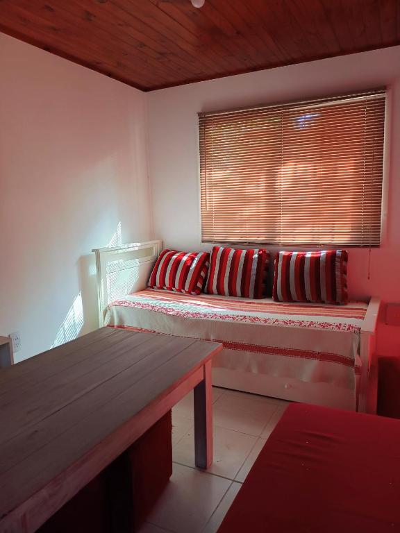 a room with a bench and a window with red pillows at Umbral del valle in Valle Hermoso