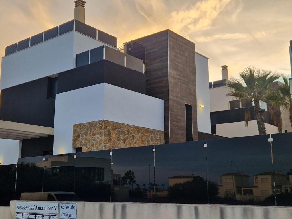a black and white building with a palm tree at Cape villa in Cabo de Roig by Perfectly Rentals in Orihuela