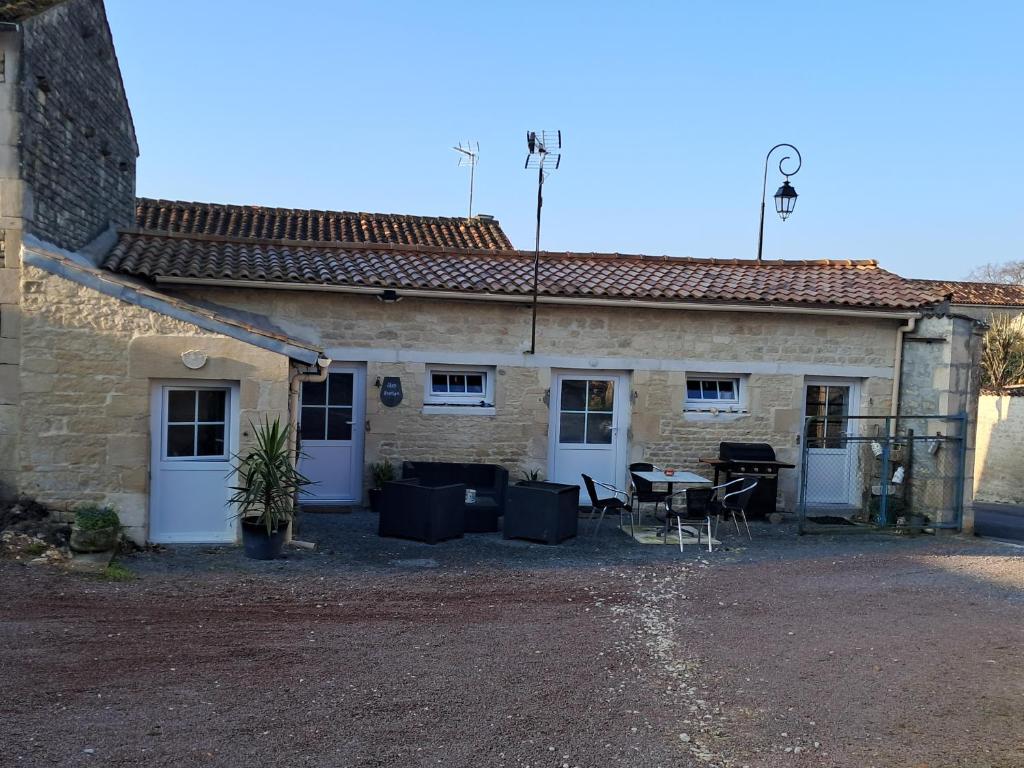 a building with a table and chairs in front of it at Chez Mamisa in Saint-Mandé-sur-Brédoire