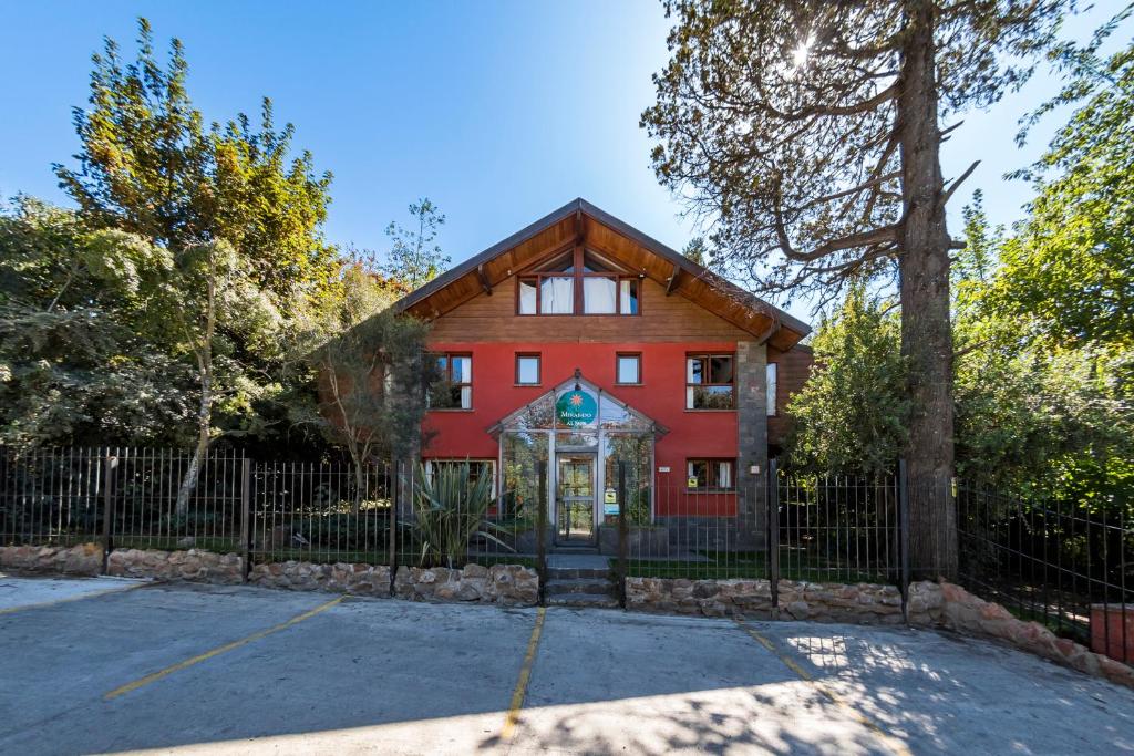 a red house with a fence in front of it at Mirando al Sur in San Carlos de Bariloche