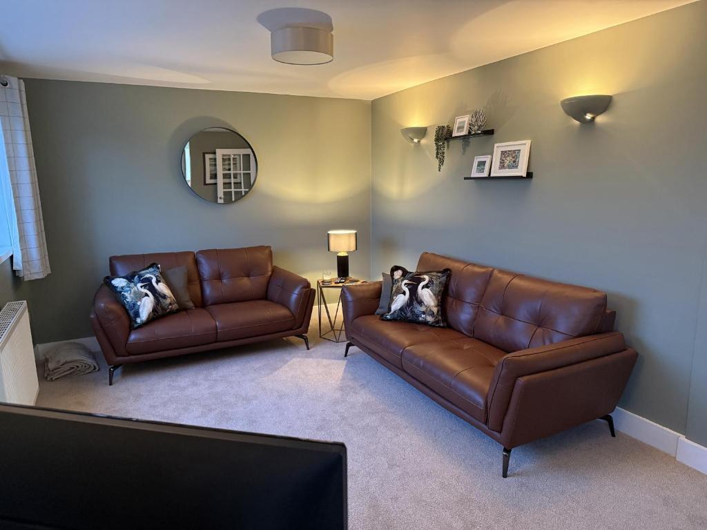 a living room with two leather couches and a mirror at Sowena in Carbis Bay