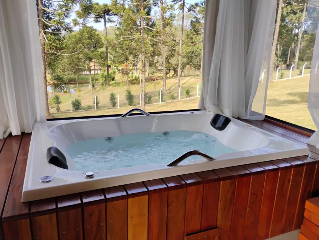 a large bath tub with a large window at Pousada Anabela in Campo Alegre