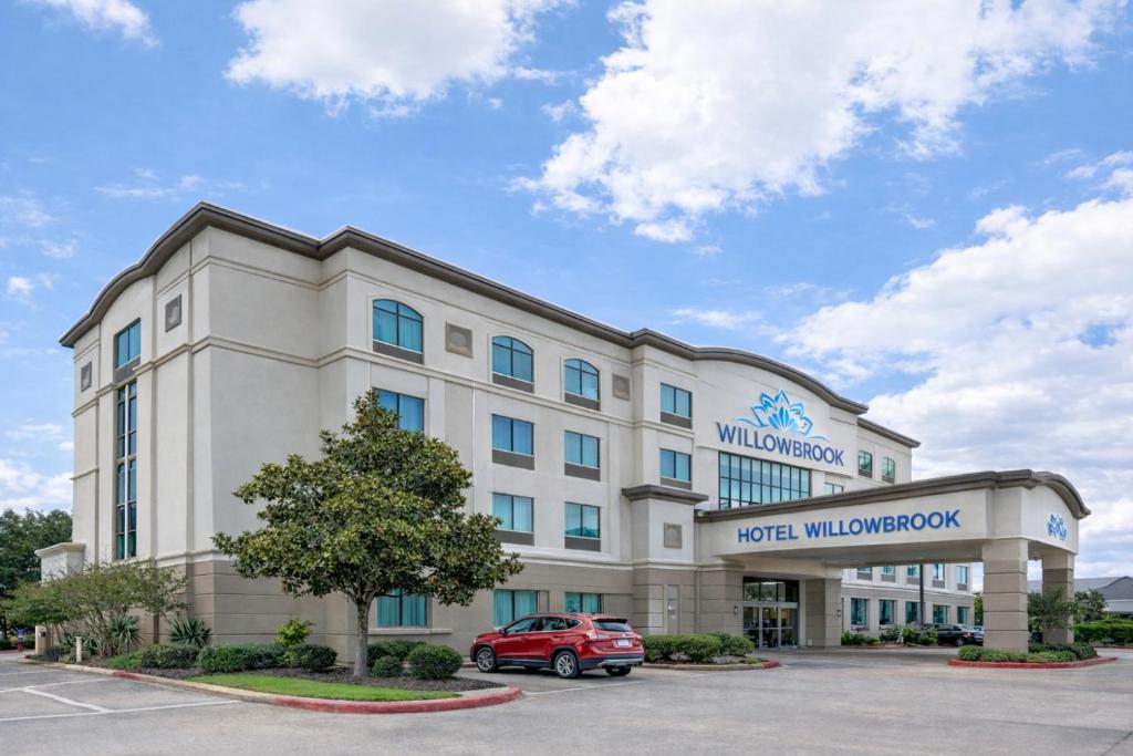 a hotel with a car parked in a parking lot at Hotel Willowbrook in Houston