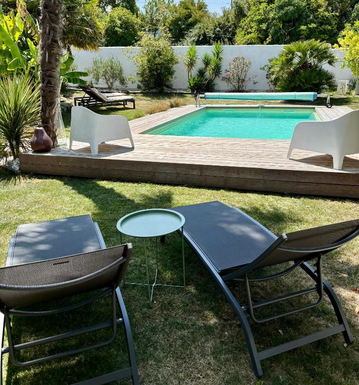 two chairs and a table next to a swimming pool at Villa avec piscine Proche de ROYAN in Sémussac