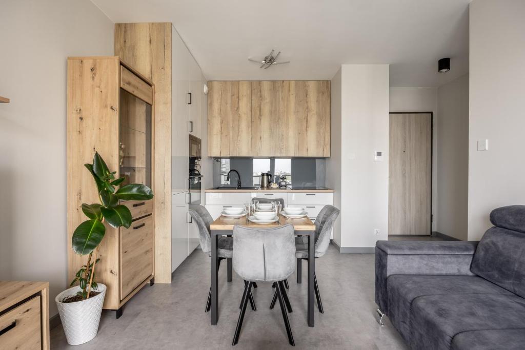 a kitchen and dining room with a table and a couch at Hygge Amber Aparts - 9th floor in Gdańsk Letnica
