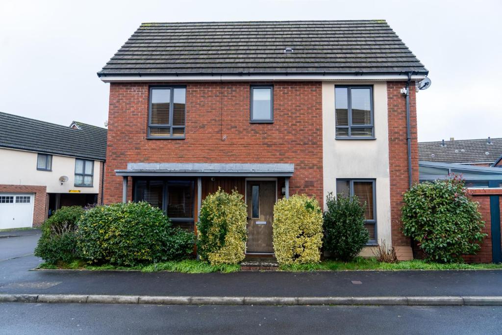 a brick house with bushes in front of a street at Vyn's Holiday home - Sleeps 6 in Cardiff