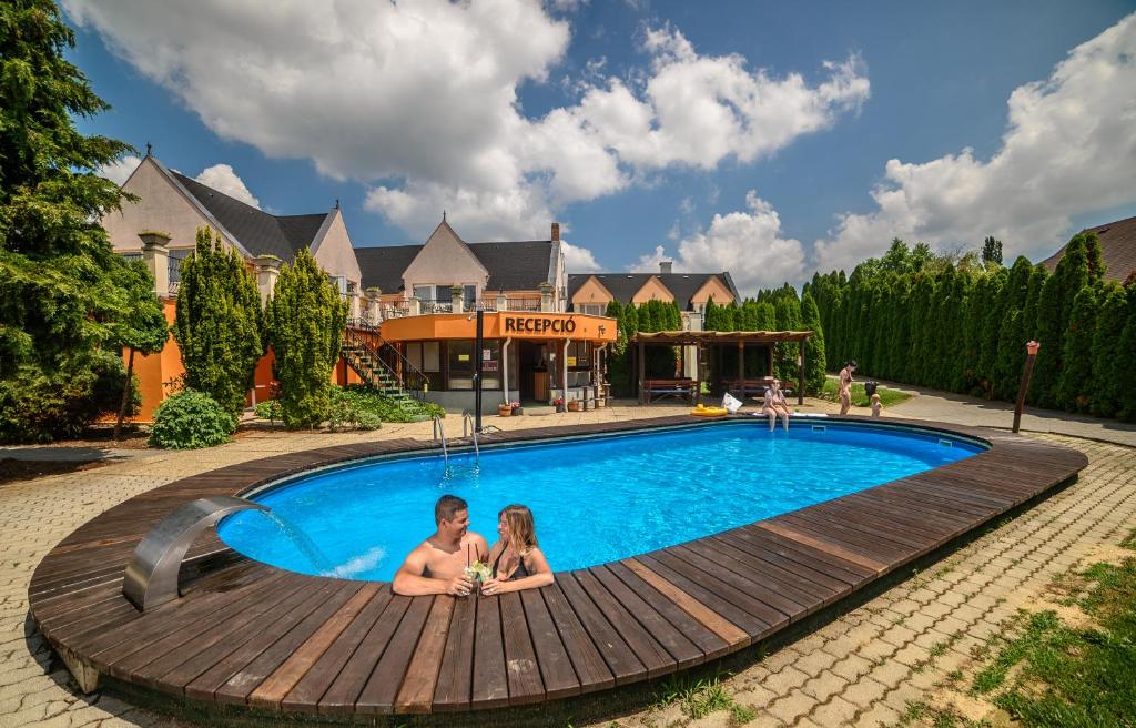 a man and a woman sitting in a swimming pool at Keller Apartman in Cserszegtomaj