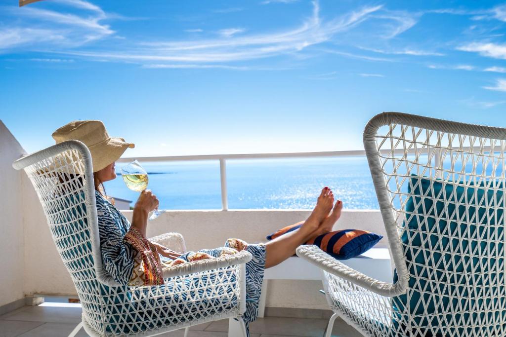 a man sitting in a chair with a glass of wine at Libera1 in Stara Baška