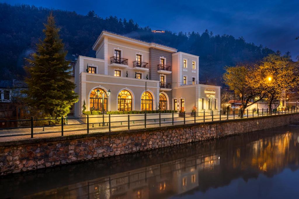 a large white building next to a river at night at Mountain Pine Luxury Suites in Florina