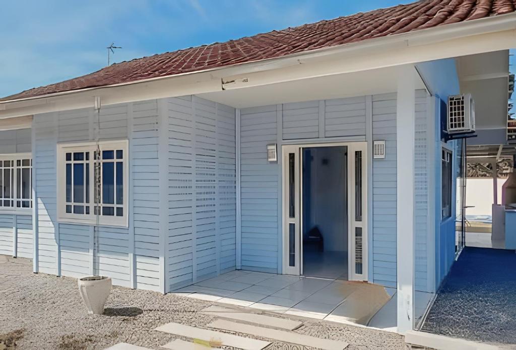 a white house with a blue door in front at Villa Di Mare 2 - Pool, fire pit, and barbecue grill in São Francisco do Sul