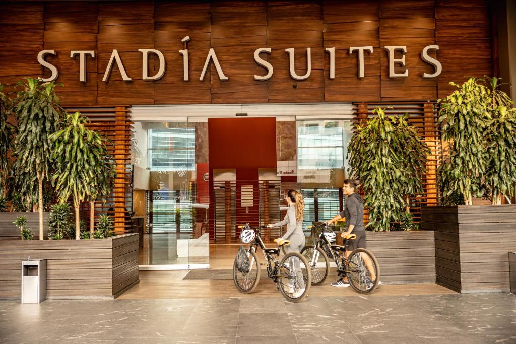 two people walking their bikes in front of a building at Stadia Suites Mexico City Santa Fe in Mexico City