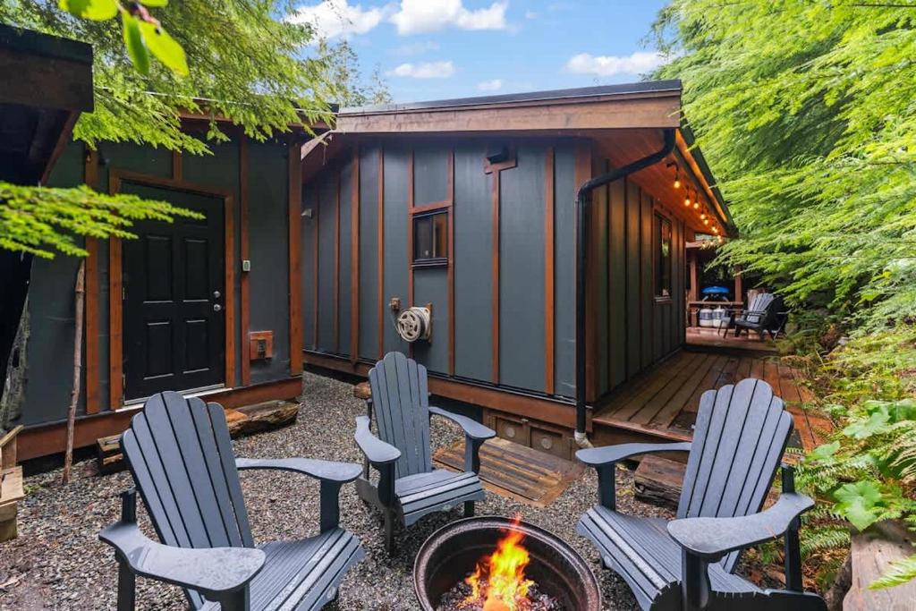 two chairs and a fire pit in front of a tiny house at JDF Waystation Cabin - Garden View - Pet Friendly in Port Renfrew