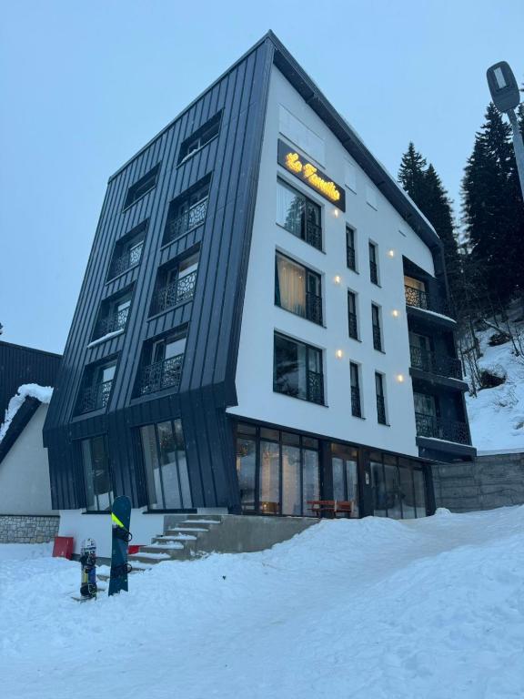 a building in the snow with a person standing in front of it at La Familia in Jahorina