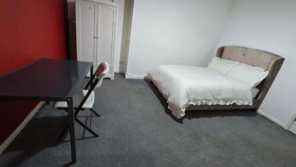 a bed in a room with a table and a chair at Precious House 4 in Leicester