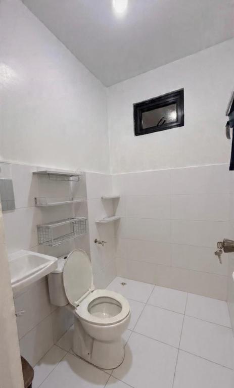 a white bathroom with a toilet and a sink at Mabini Homestay in Mabini