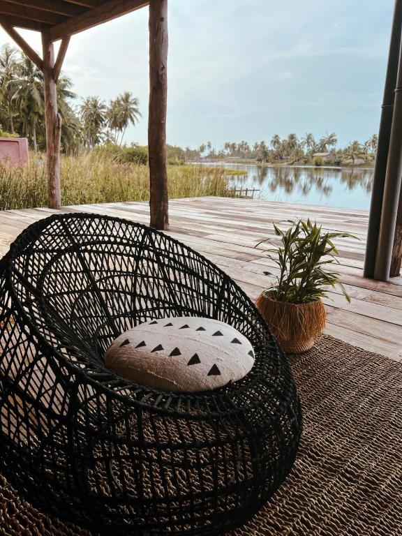 a wicker chair sitting on a rug next to a lake at Villa Aïdo in Ouidah
