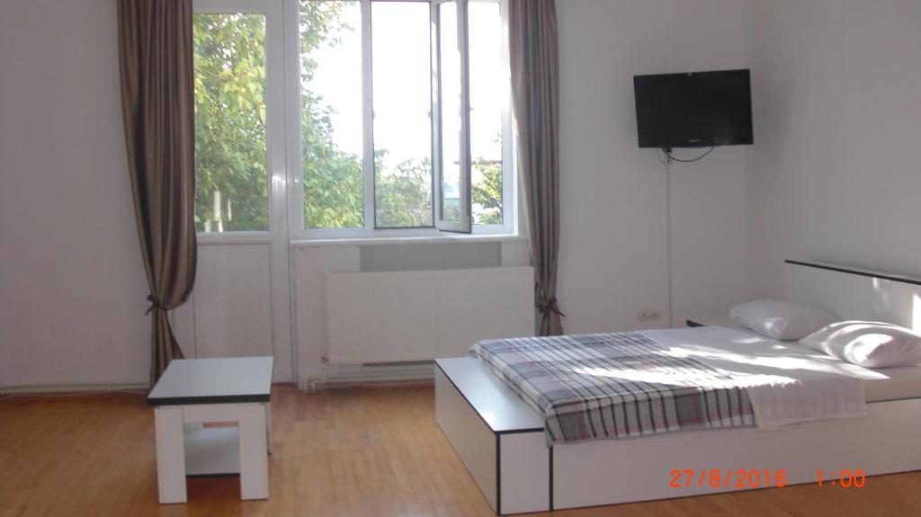 a white bedroom with a bed and a tv at Villa House Georgia in Tbilisi City