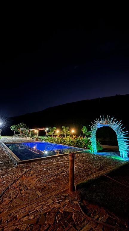 a swimming pool at night with a blue fountain at Chalé São Bernardo, Carmo RJ in Carmo
