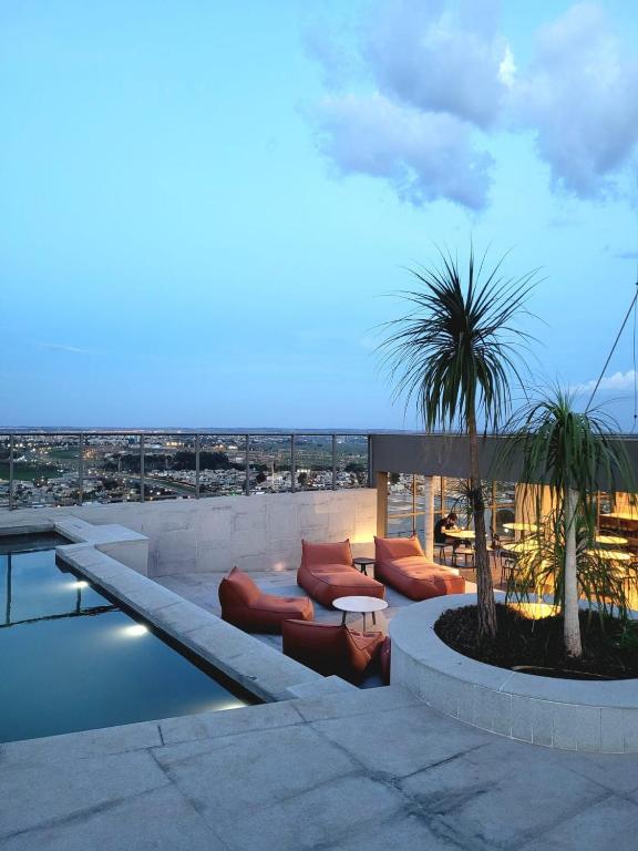a rooftop patio with couches and a palm tree at Condomínio Residencial - Hype 017 | by Housi in Sao Jose do Rio Preto