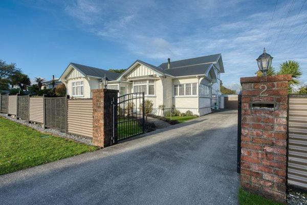 a white house with a gate and a fence at Delight On Dalton in Hokitika