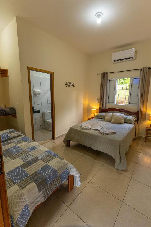 a bedroom with two beds and a bathroom at Pousada Morada do Paraíso in Torrinha