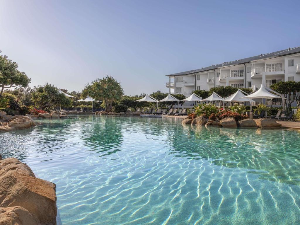 a large swimming pool in a resort with umbrellas at Mantra on Salt Beach in Kingscliff
