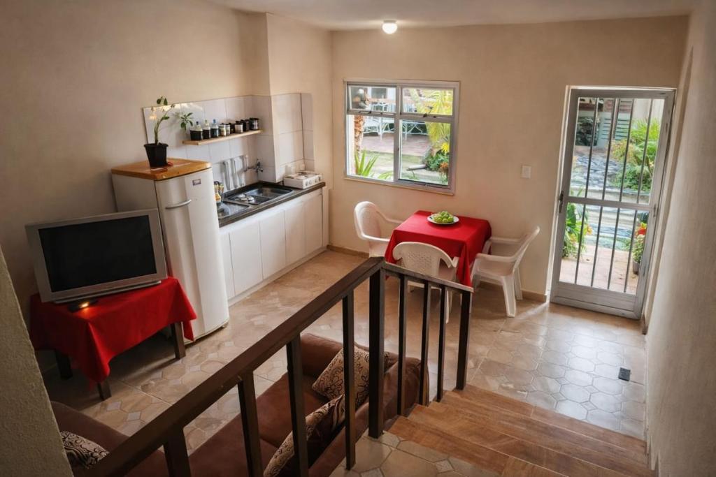 a living room with a television and a kitchen at Pousada Rancho in Angra dos Reis
