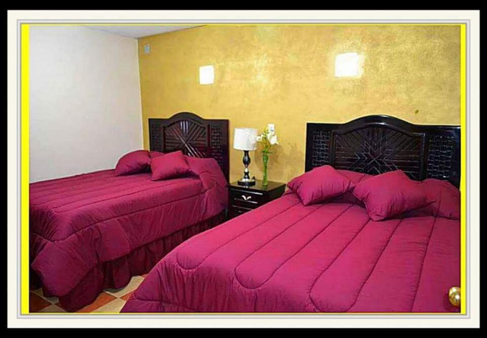 a bedroom with two beds with pink covers at Hotel Milenio Nanacamilpa Tlaxcala in Nanacamilpa