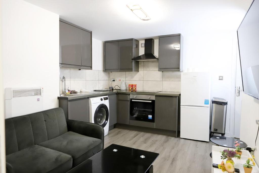 a living room with a couch and a kitchen at The Apartment in Oldham