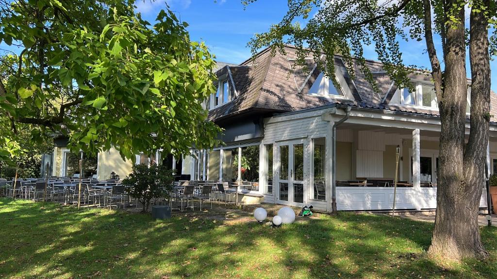 a house with chairs and a tree in the yard at Hotel Belvedere in Seevetal