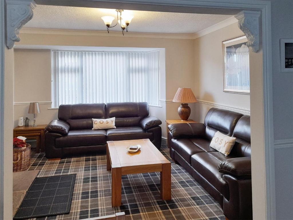 a living room with a leather couch and a table at Wheelhouse 21 in Amble