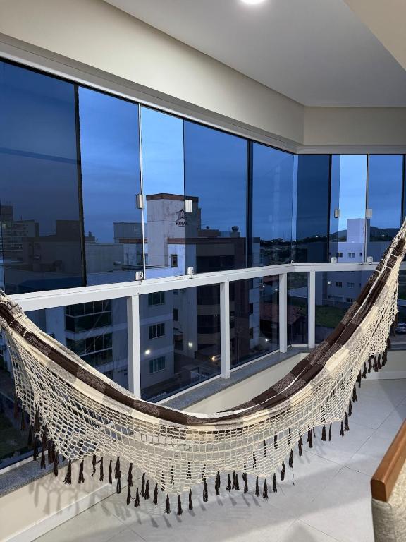 a hammock on a balcony with a view of the city at Refúgio Vila Mar Apto in Imbituba