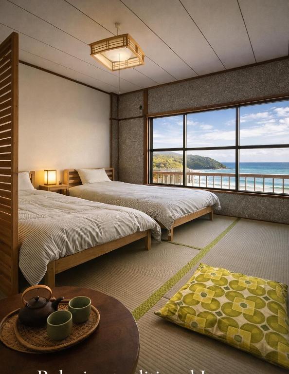 two beds in a room with a view of the ocean at MACARA Guesthouse in Nichinan