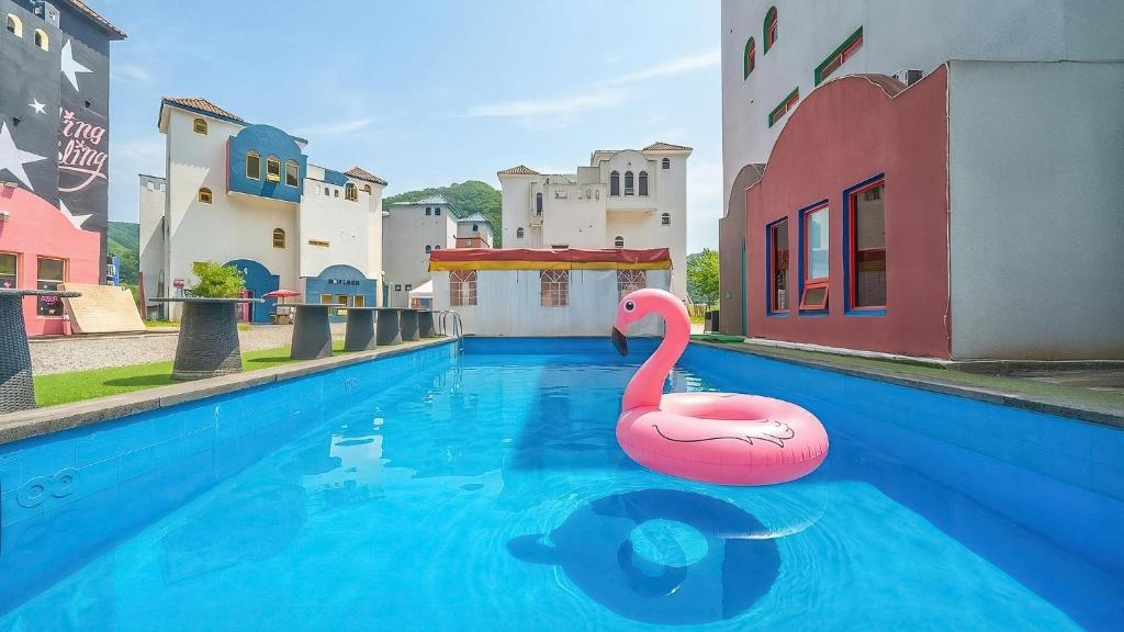 a swimming pool with a pink swan in the water at Chuncheon Vishop Pension in Chuncheon