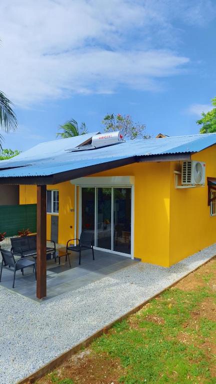 una casa gialla con un tetto e un patio di Emma modern suite a Kourou