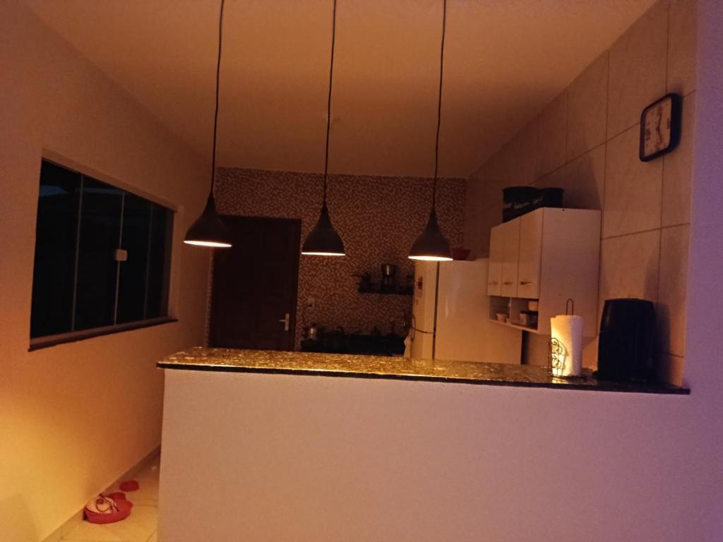 a kitchen with a counter with a refrigerator and pendant lights at Hostel de clecia in Extremóz