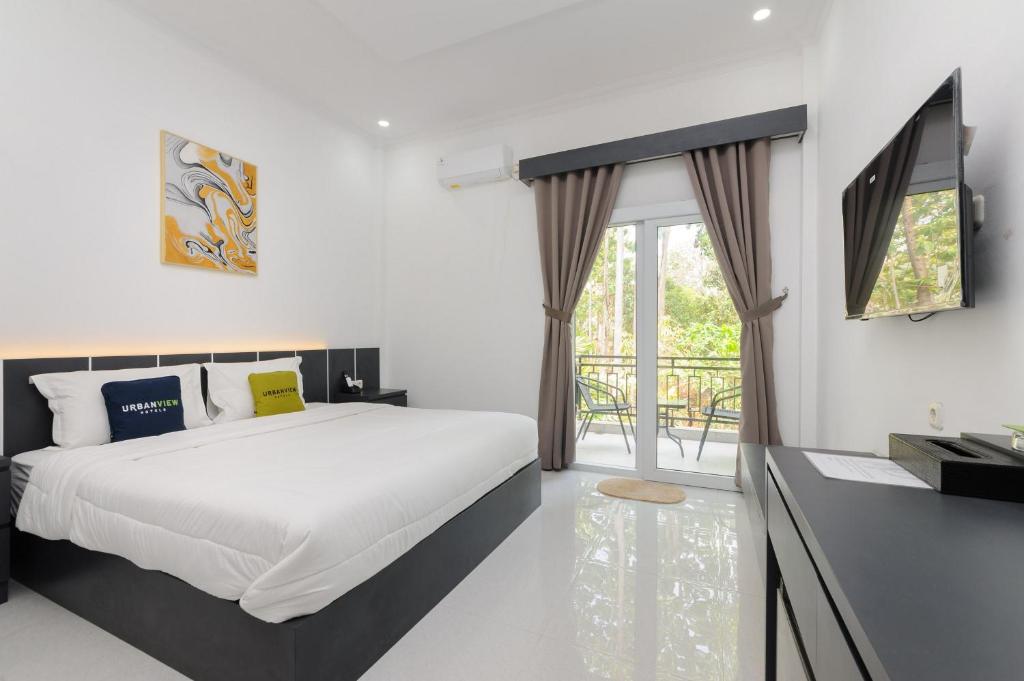 a bedroom with a large bed and a balcony at Urbanview Hotel AnD Lampung by RedDoorz in Lampung