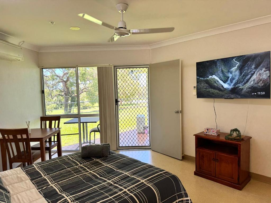 a bedroom with a bed and a table and a tv at Bulgon Lodge in Collinsville