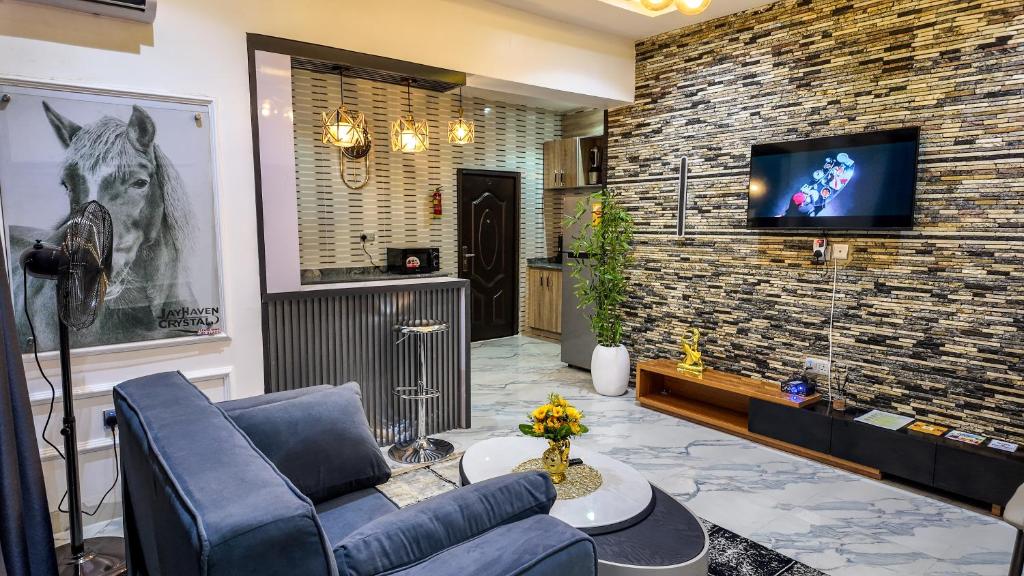 a living room with a couch and a tv on a brick wall at Jayhaven Crystal Serviced Apartment in Uyo