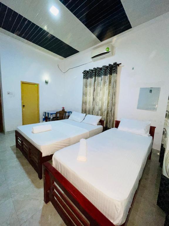 two beds are in a room with at Golden Palace Yala in Tissamaharama