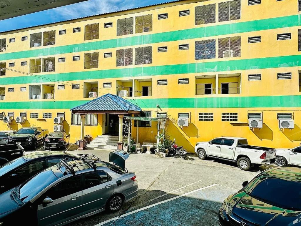 a yellow building with cars parked in front of it at เพิ่มพูนแมนชั่น พิษณุโลก Phoempun Mansion in Sathani Phitsanulok