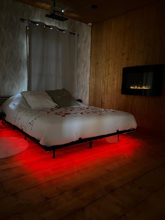 a bed in a room with red lights on the floor at Ô Chalet Normand in Colomby