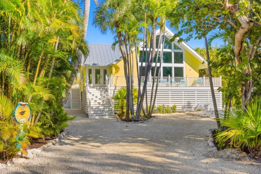 a yellow house with palm trees in front of it at Amarelo Sol in Captiva