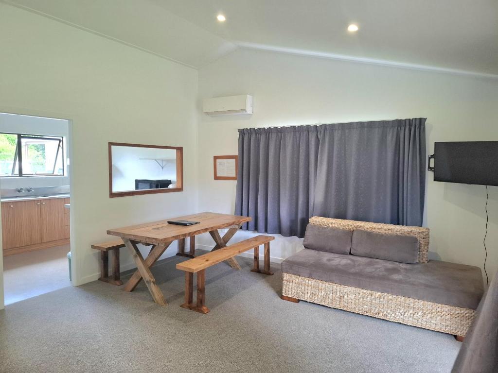 a living room with a table and a couch at Seabreeze Holiday Park in Hotwater Beach